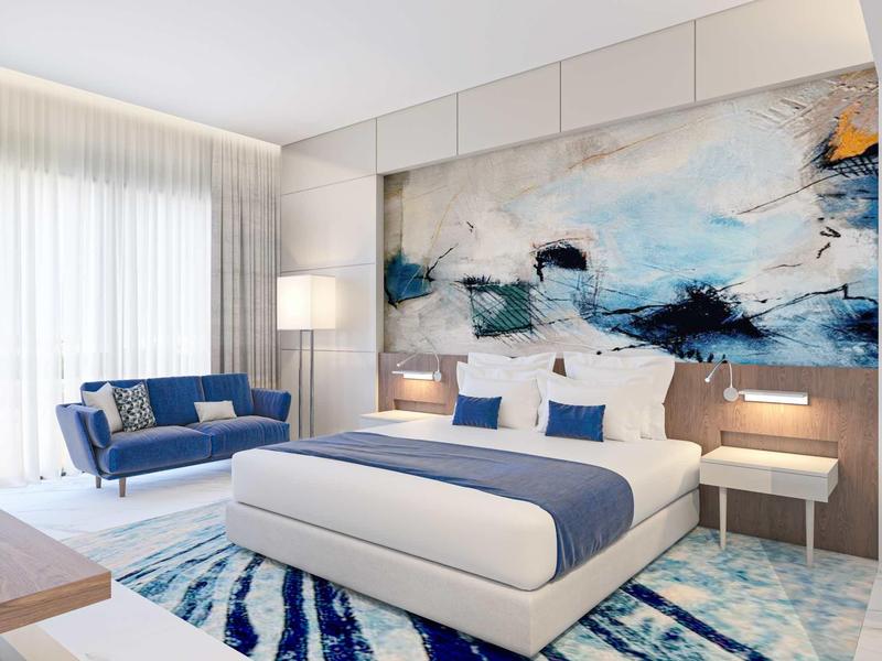 Modernes Schlafzimmer mit blau-weißem Farbkonzept, großem Bett und abstraktem Wandbild.