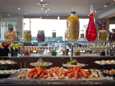 Buffet con varios aperitivos y mariscos en un restaurante de hotel moderno y luminoso.
