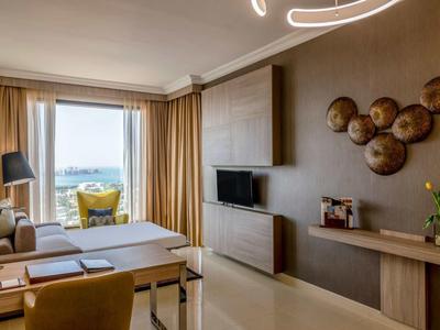 Habitación de hotel moderna con terraza, vista al agua y asientos confortables.