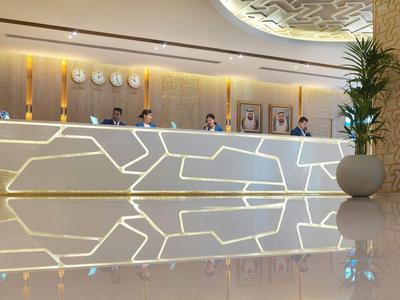 Recepción moderna de la lobby del hotel con mostrador iluminado y plantas en maceta.