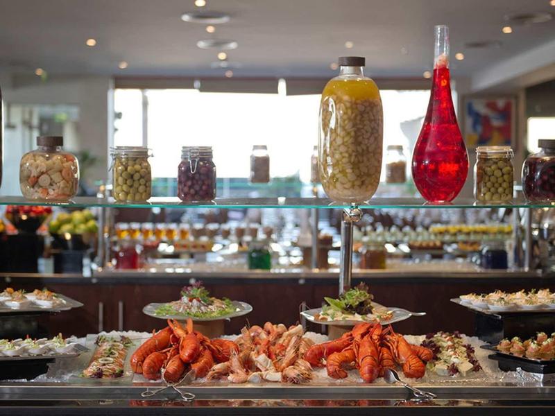 Buffet con varios aperitivos y mariscos en un restaurante de hotel moderno y luminoso.