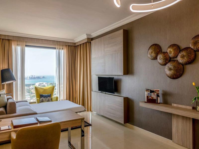 Habitación de hotel moderna con terraza, vista al agua y asientos confortables.