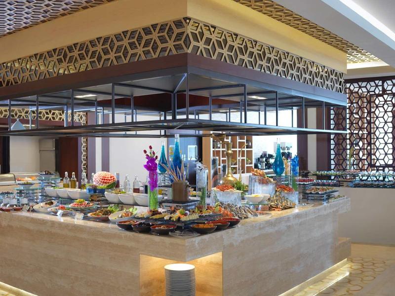 Área de buffet en un restaurante moderno de hotel con variedad de platos y iluminación decorativa.