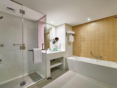Moderne badkamer met douche, ligbad en grote spiegel in een hotel.