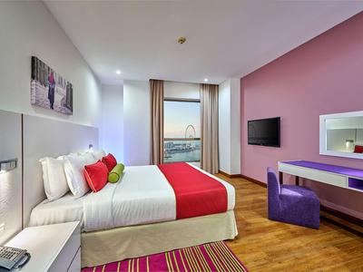 Moderne hotelkamer met tweepersoonsbed, rode accenten, bureau en uitzicht op het water