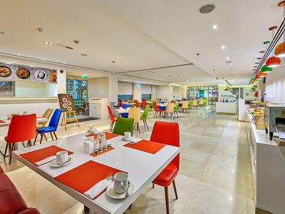 Jasna, nowoczesna sala śniadaniowa z kolorowymi krzesłami i nakrytymi stołami w hotelu.