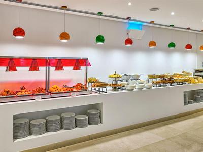 Buffet con illuminazione per cibi caldi e una selezione di prodotti per la colazione in un hotel moderno.
