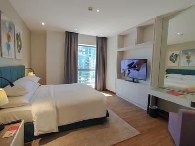 Camera d'hotel moderna con letto grande, TV a parete e finestra con vista su edifici.