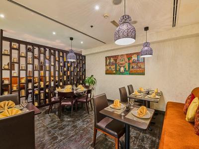 Moderní hotelová restaurace s dřevěným nábytkem, prostřenými stoly a teplým osvětlením.