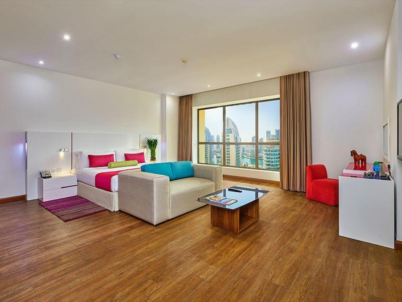 Moderne hotelkamer met groot tweepersoonsbed, zithoek, groot raam en houten vloer.