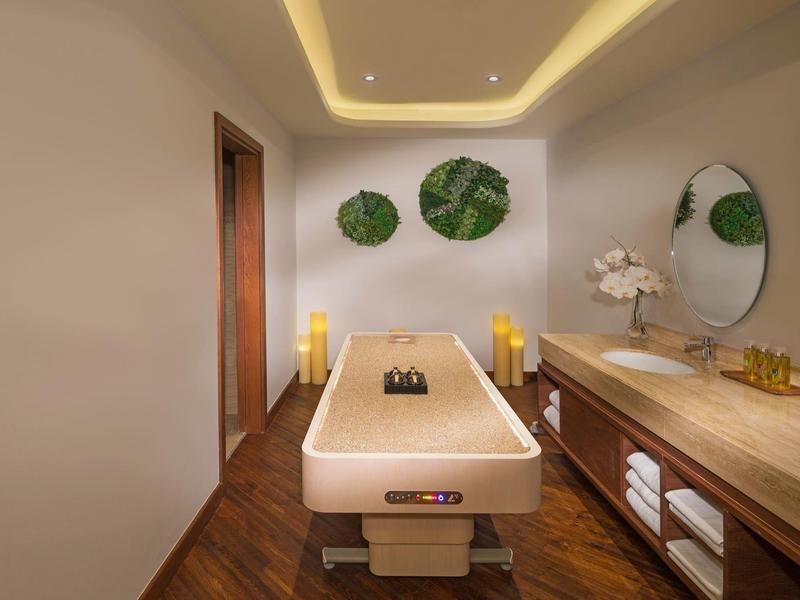 Modern behandelkamer met massagetafel, houten vloer en warm licht.