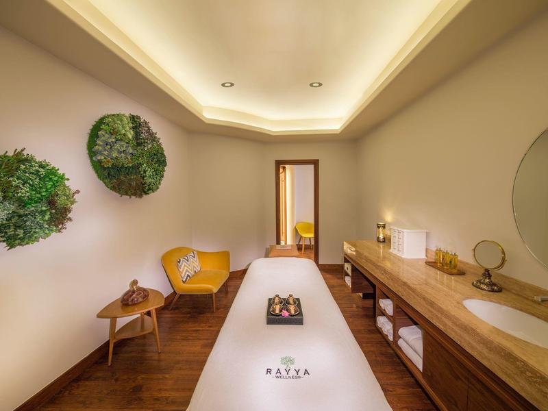 Elegante wellnessruimte met massagetafel, houten meubels en rustgevende verlichting.