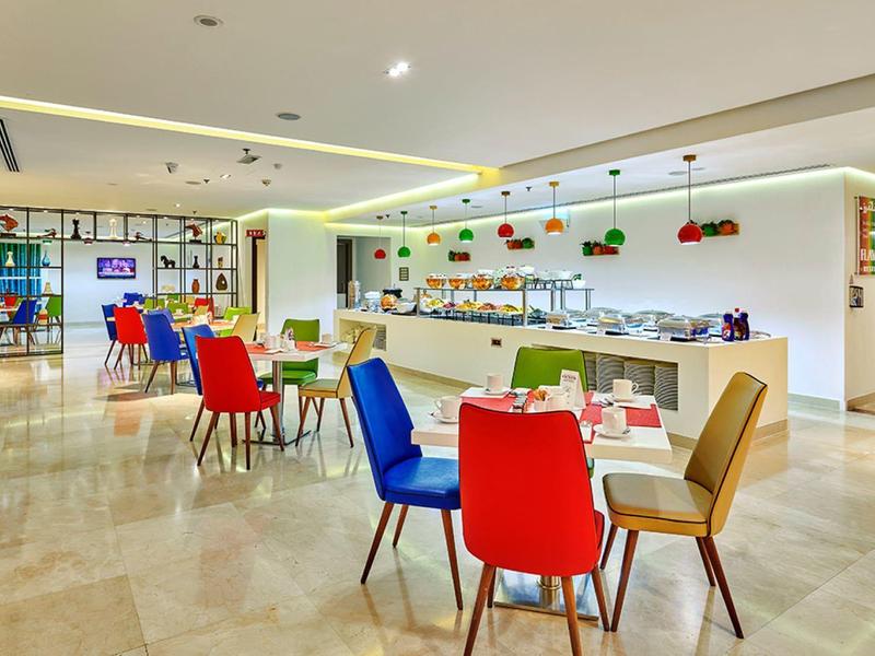 Moderne, lichte eetruimte met kleurrijke stoelen en grote ramen.