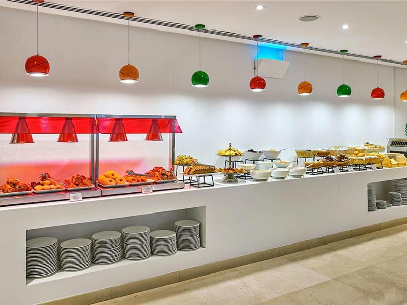 Buffet met warme en koude gerechten, gedecoreerd met kleurrijke lampen in een modern restaurant.