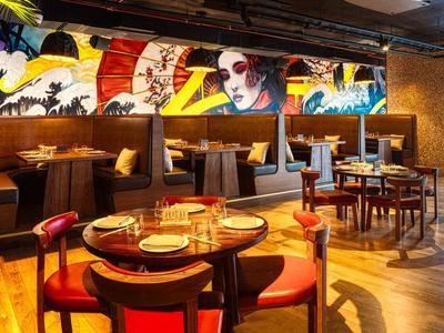 Restaurante moderno con mural colorido y asientos cómodos.