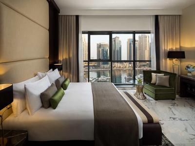 Modern hotel room with large bed, floor-to-ceiling windows, and city view.