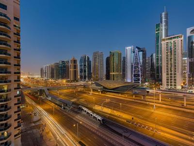 Urban high-rise buildings and multi-lane road at dusk with flowing traffic.