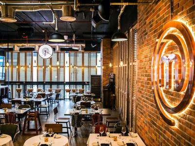Interior moderno de restaurante con paredes de ladrillo, detalles de madera y metal, y mesas elegantemente preparadas.