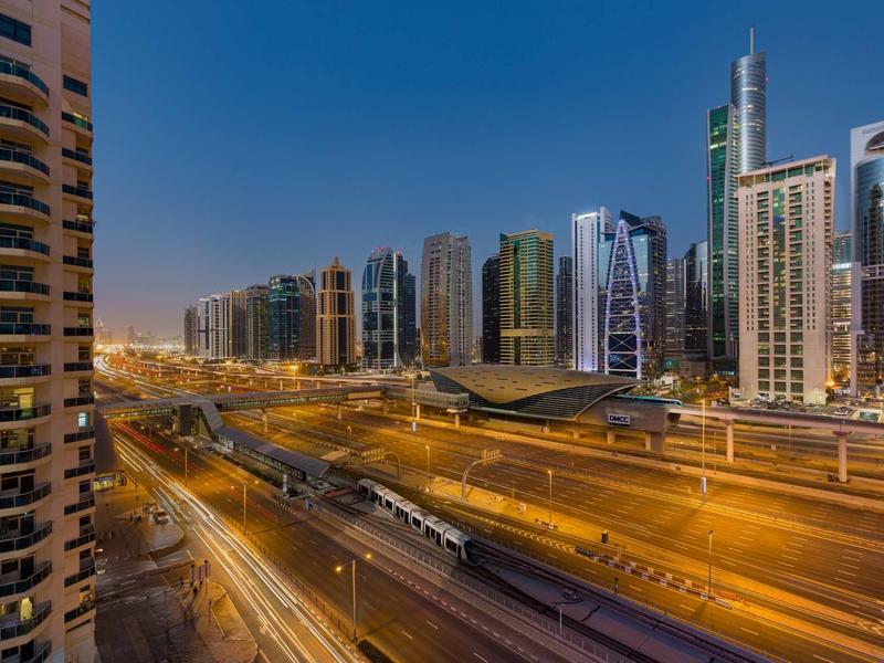 Urban high-rise buildings and multi-lane road at dusk with flowing traffic.