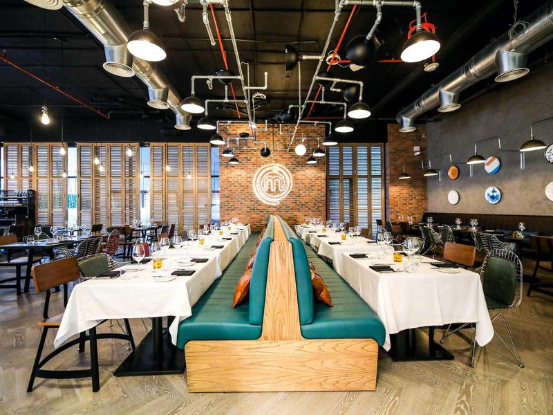 Modern restaurant interior with blue booths and white tablecloths in an elegant setting.