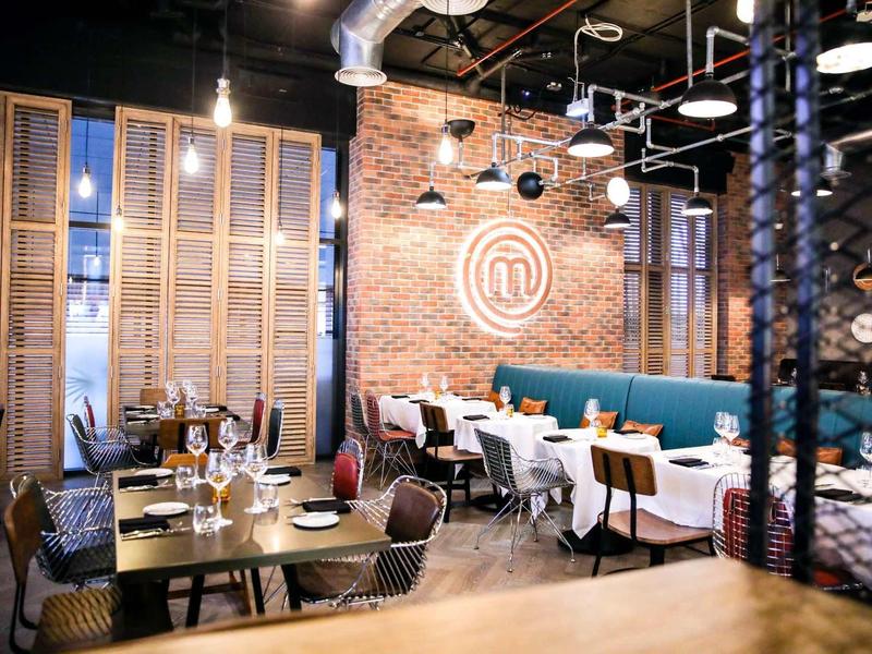 Modern restaurant with brick wall, illuminated logo, and stylish decor.