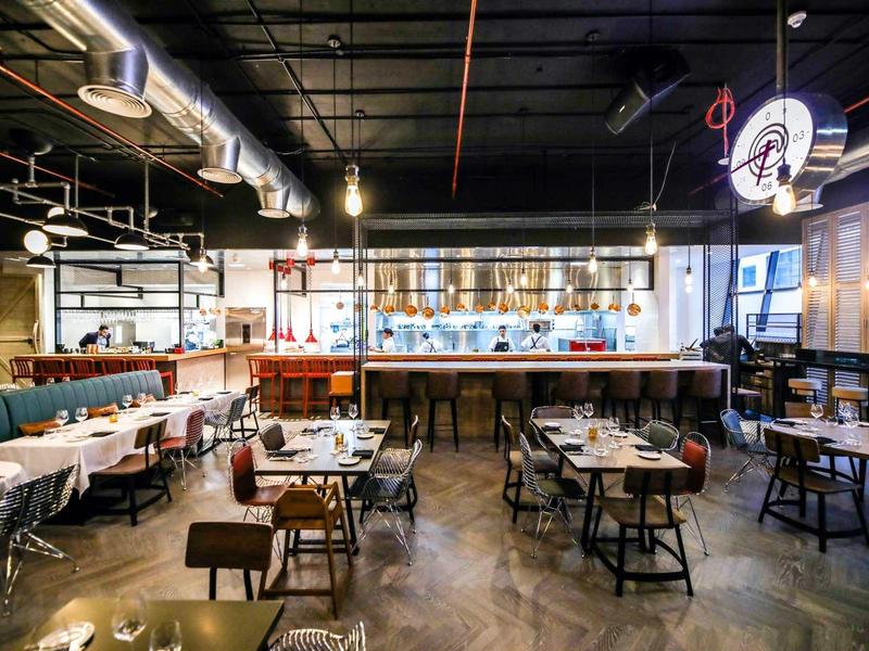 Modern restaurant with wooden tables, comfortable chairs, and stylish lighting.