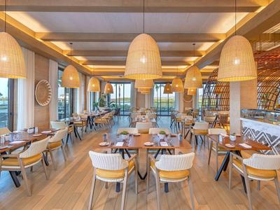 Modernes Restaurant mit Holzstühlen und großen Korblampen, hell und einladend.