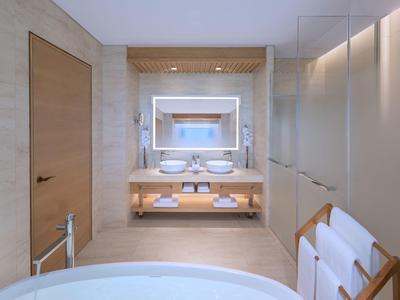 Modernes Badezimmer mit Doppelwaschbecken, beleuchtetem Spiegel und freistehender Badewanne.