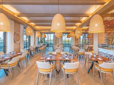 Modernes, helles Restaurant mit Holzmöbeln und großen Hängeleuchten.