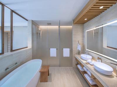 Modernes Badezimmer mit freistehender Badewanne, Doppelwaschbecken und großem beleuchtetem Spiegel.