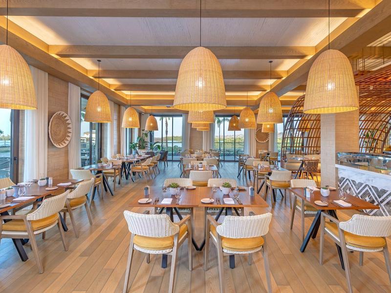 Modernes Restaurant mit Holzstühlen und großen Korblampen, hell und einladend.