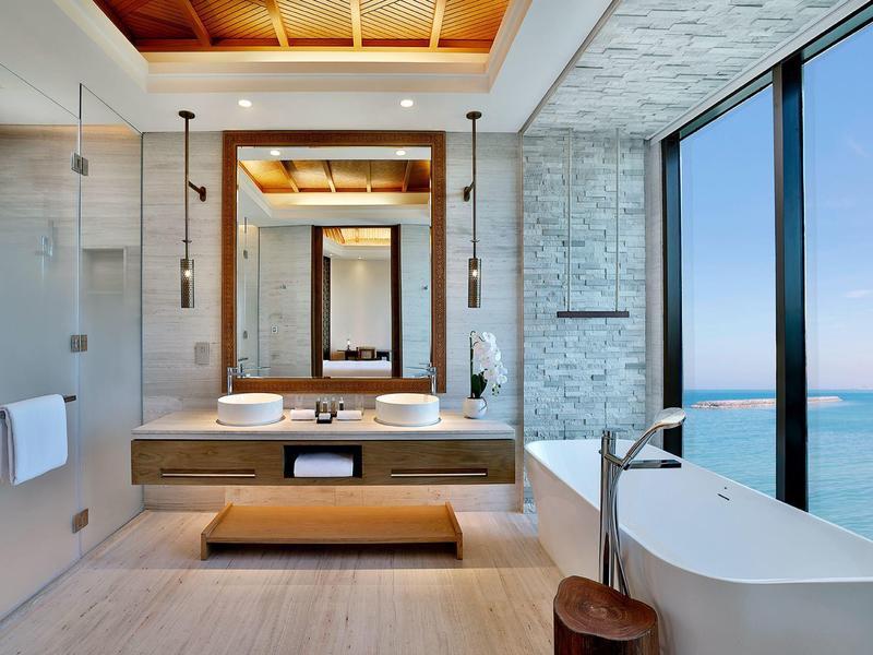 Helles Badezimmer mit freistehender Badewanne und großem Fenster mit Meerblick.