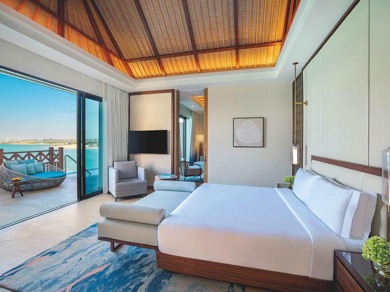 Helles Hotelzimmer mit Doppelbett, Sitzbereich und Zugang zu einem Balkon mit Meerblick.