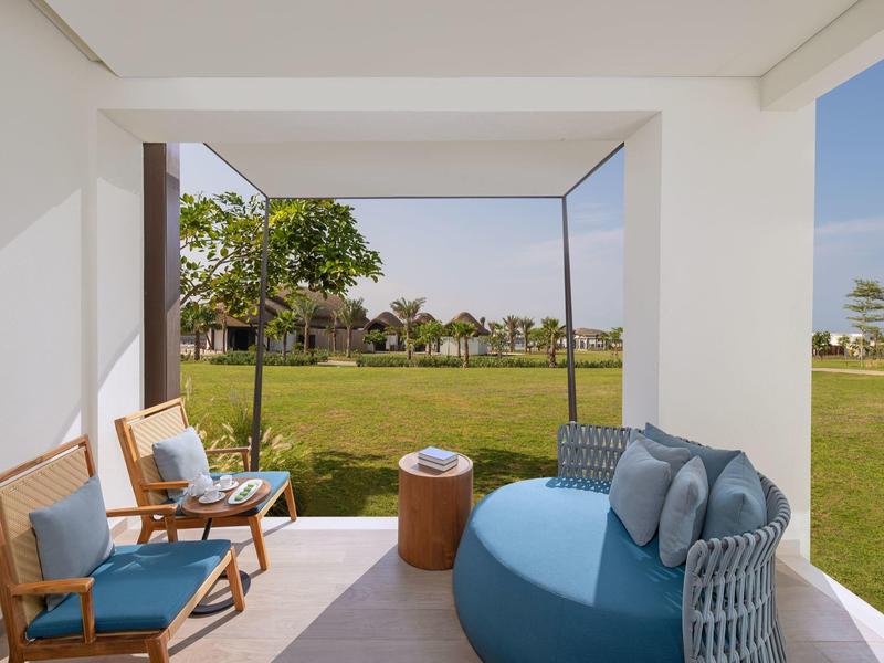 Überdachte Terrasse mit modernen Sitzmöbeln und Blick auf einen grünen Garten.