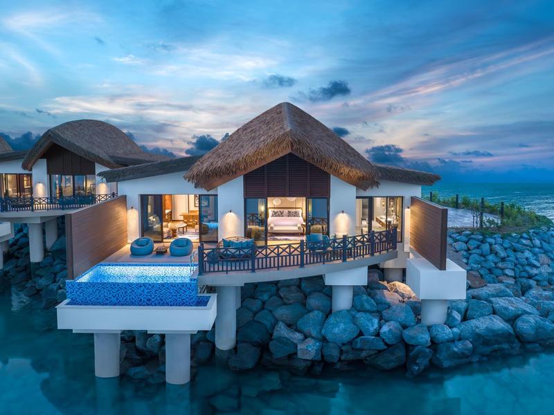 Luxusüberwasserbungalow mit Pool und Meerblick bei Sonnenuntergang