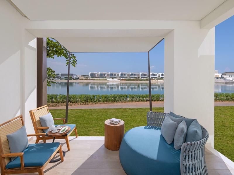 Moderner Terrassenbereich mit gemütlichen Sitzmöbeln und Blick auf Wasser und Häuser.