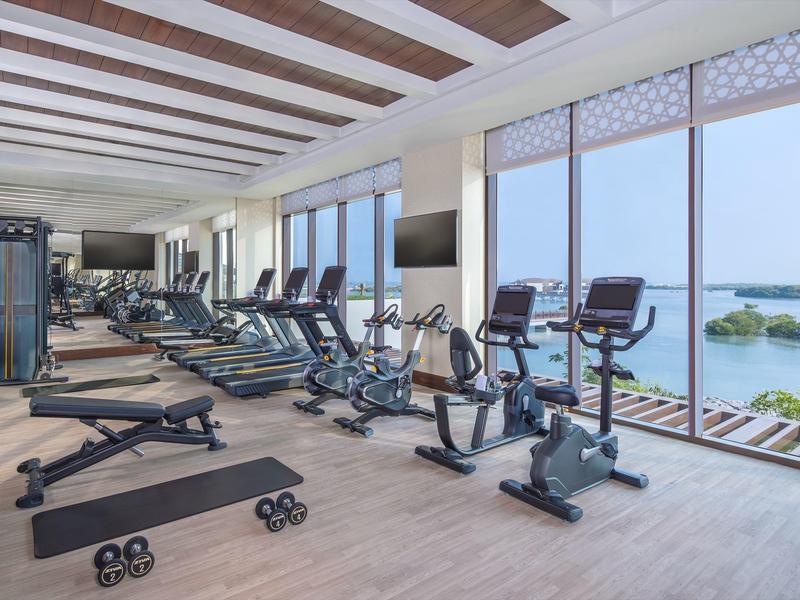 Heller Fitnessraum mit modernen Geräten und Panoramafenstern mit Meerblick.