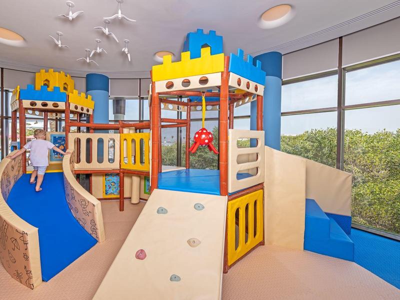 Kinderspielbereich mit Rutschen und Klettergeräten in einem sonnendurchfluteten Raum