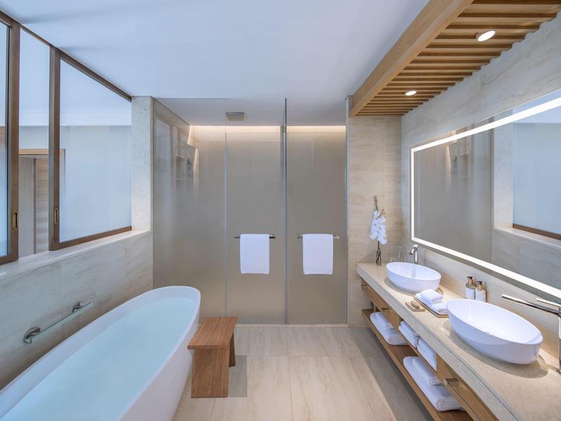 Modernes Badezimmer mit freistehender Badewanne, Doppelwaschbecken und großem beleuchtetem Spiegel.