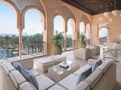 Terrace with comfortable white sofas and large arches overlooking plants and lake.