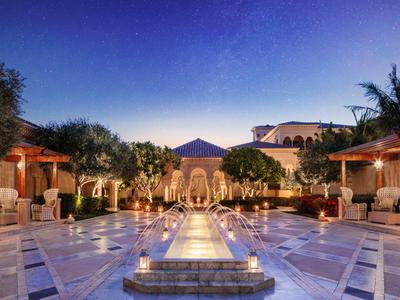 Luxurious courtyard with water feature and seating areas under clear night sky.