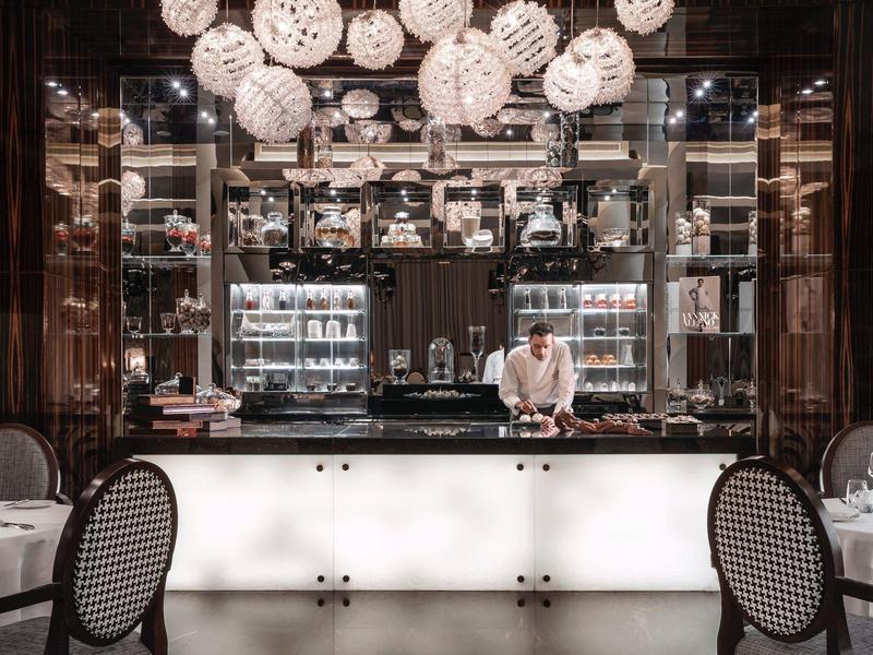 Elegante Bar mit beleuchtetem Tresen und dekorativen Lampen, Kellner hinter der Theke.