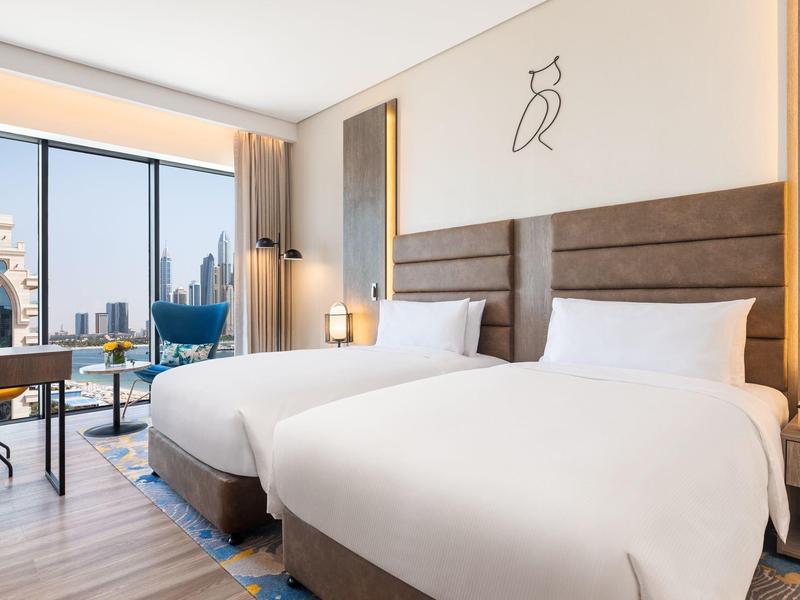 Modernes Hotelzimmer mit zwei großen Betten, bodentiefen Fenstern und Stadtblick.