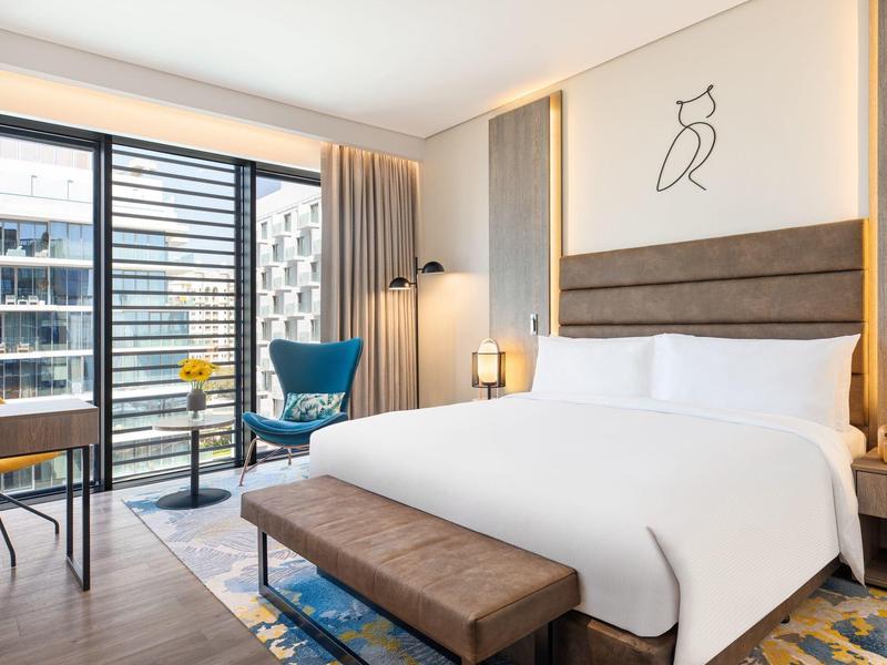 Helles Schlafzimmer mit großem Bett, blauer Sitzbank, Balkon und moderner Dekoration.