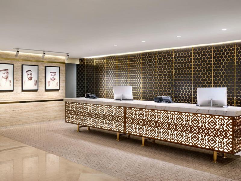 Ein eleganter Hotelempfang mit einem dekorativen Empfangstresen und Kunstwerken an der Wand.