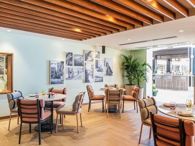 Gezellige eetruimte met houten plafond, moderne tafels en stoelen, en heldere sfeer.