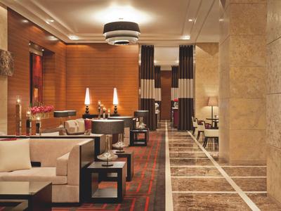 Luxe hotellobby met beige banken, warm licht en een marmeren vloerpand.