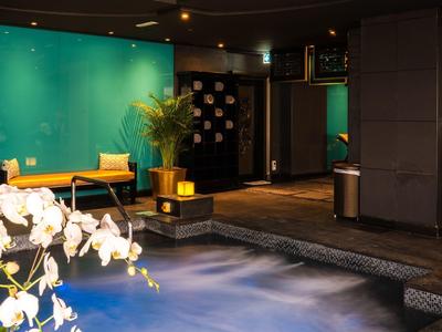 Moderne hotel lobby met blauwe sfeerverlichting, een gele stoel en sierplanten.