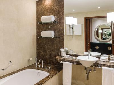 Moderne badkamer met bad, wastafel, spiegel en wandlampen.