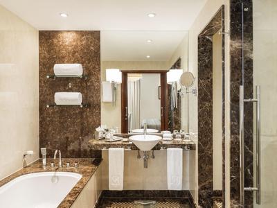 Nowoczesna łazienka z wanną, podwójnymi umywalkami i marmurowymi akcentami.